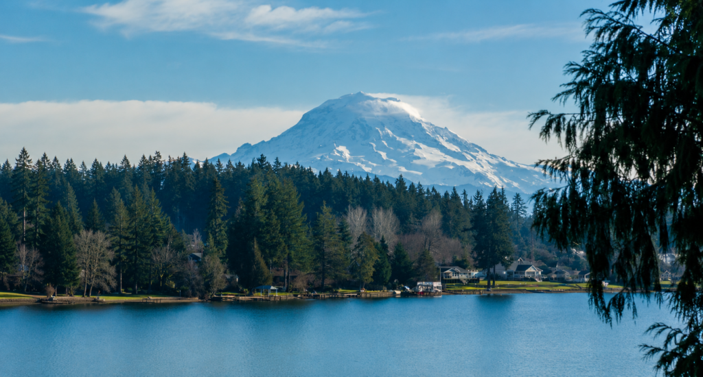 Snow-capped Mount Rainier towers over Bonney Lake, framed by lush trees and serene waters, ideal for Bellevue Limousine Service.
